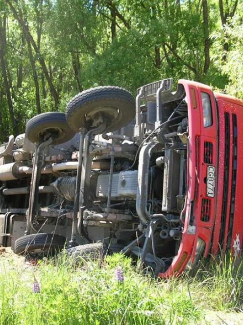 A furniture truck lies on its side down a bank near Tarras yesterday. Photo by Rosie Manins.