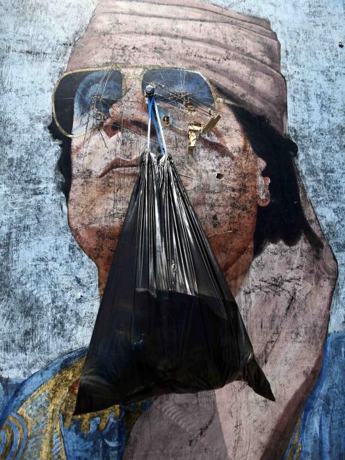 A garbage bag hangs from a portrait of Muammar Gaddafi in Tripoli.  (REUTERS/Zohra Bensemra)