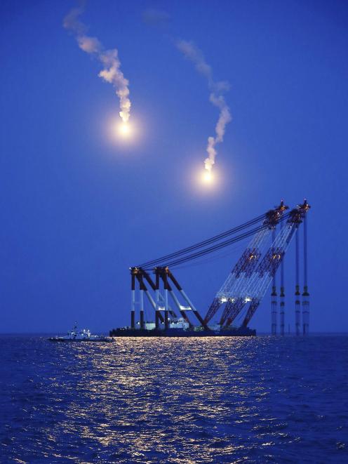 A giant offshore crane which will be used in a night rescue operation, is seen near flares at the...