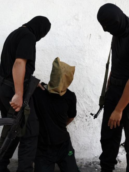 A Hamas militant grabs a Palestinian suspected of collaborating with Israel, before being...