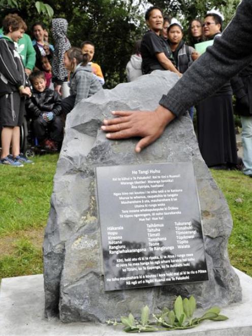 A hand touches a memorial stone during a ceremony at the Southern Cemetery in Dunedin yesterday....