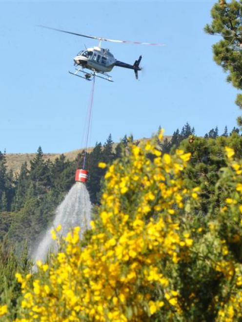 A helicopter-borne  monsoon bucket is used to dampen the remains of a forest fire near Dunedin on...