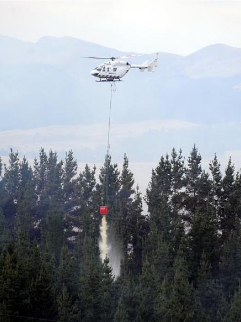 A helicopter drops a monsoon bucket of water on the plantation fire near Palmerston on Sunday....