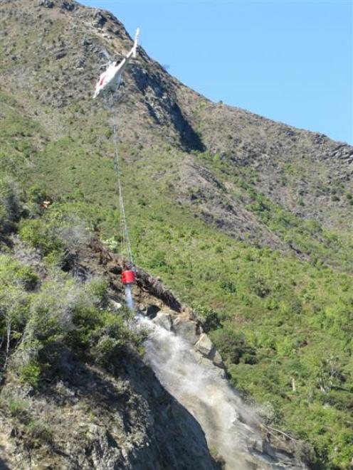 A helicopter is used to sluice the face of a slip above State Highway 6 near Makarora on...