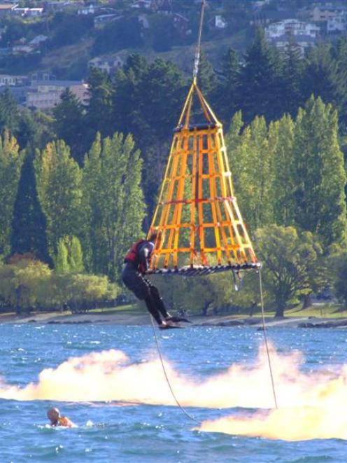 A helicopter lowers a basket and a rescuer into Lake Wakatipu during a rescue demonstration...