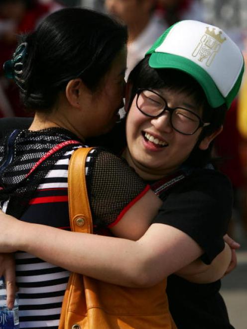 A high-school graduate embraces her mother prior to taking the National College Entrance...