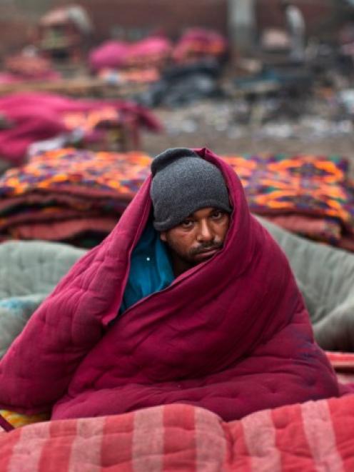 A homeless man wrapped in a quilt sits in an open space on a cold winter morning in the old...