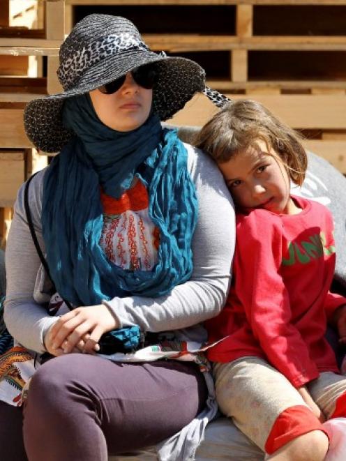 A Jordanian UN volunteer sits with a Syrian refugee child at the Al Zaatri refugee camp in the...