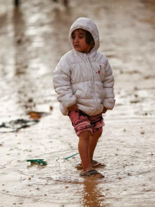 A Kurdish refugee child from the Syrian town of Kobani walks in the rain in a camp in the...