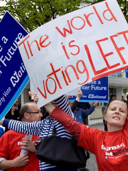 A Labour Party supporter holds her sign in front of a National Party supporter as the two groups...