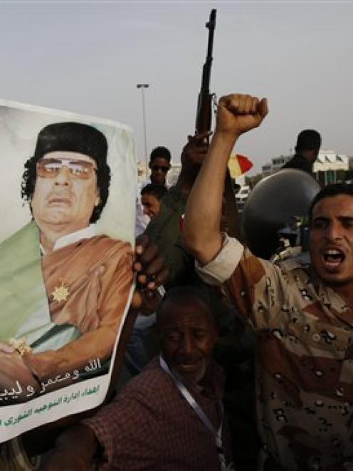 A Libyan man shouts as he and others rally next to Muammar Gaddafi's Bab al-Aziziya compound, a...