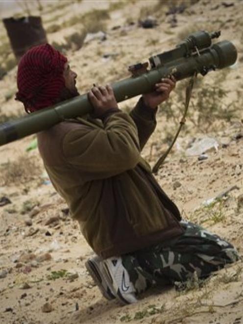 A Libyan rebel points his weapon towards forces of Muammar Gaddafi, after mortars where fired on...