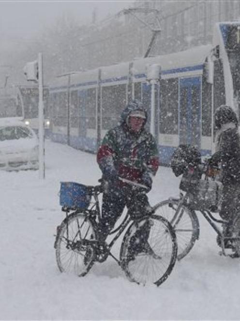 A line of stranded trams is seen as cyclists try and cross the road in heavy snow in Amsterdam. ...