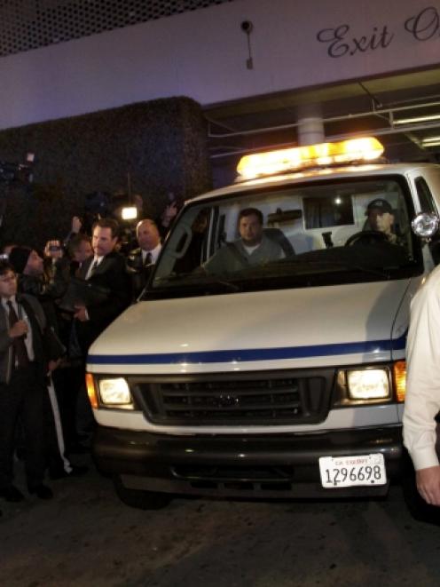 A Los Angeles County Coroners' van exits the Beverly Hilton Hotel with the body of Whitney...