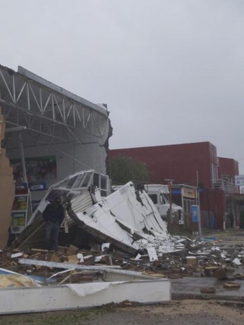 A ma walks past debris outside a store damaged after Hurricane Odile hit La Paz, in Baja...