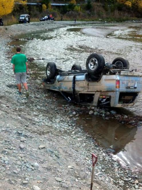 A man inspects the damage to a 4WD on Monday afternoon after the vehicle landed on its roof in...