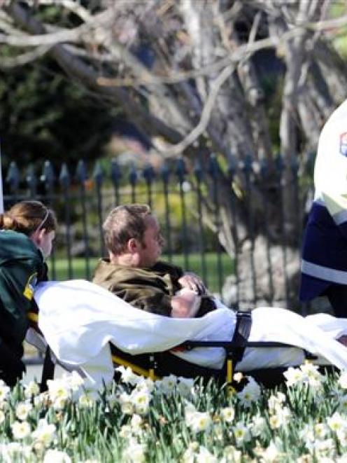A man is carried to a waiting ambulance in North Dunedin yesterday after being burnt in an...