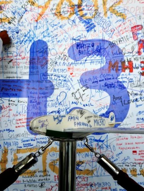 A man leaves a message of support and hope for passengers of the missing airliner at the Kuala...