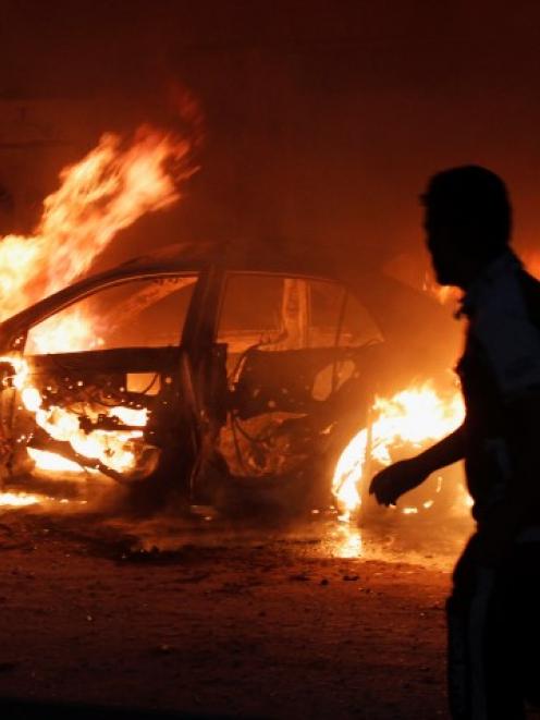 A man looks at a car on fire at the site of a bomb attack in Baghdad. REUTERS/Ahmed Saad