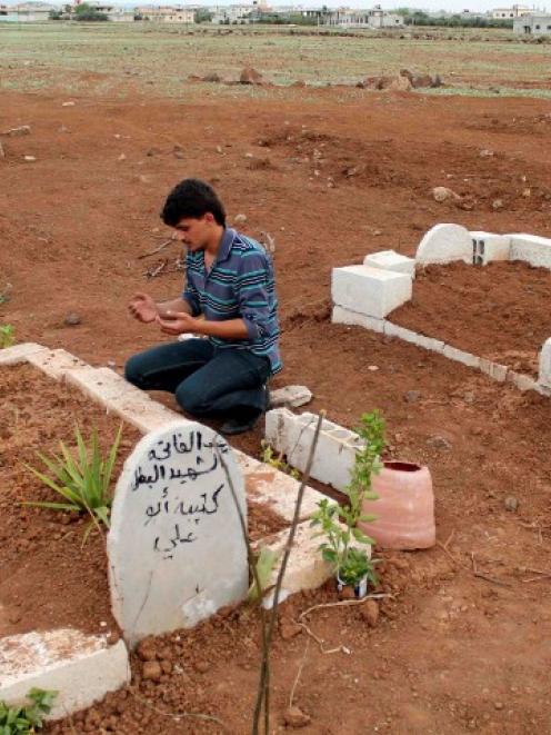 A man prays at the grave of a Free Syrian Army fighter at a cemetery at al-Karak al-Sharqi in...