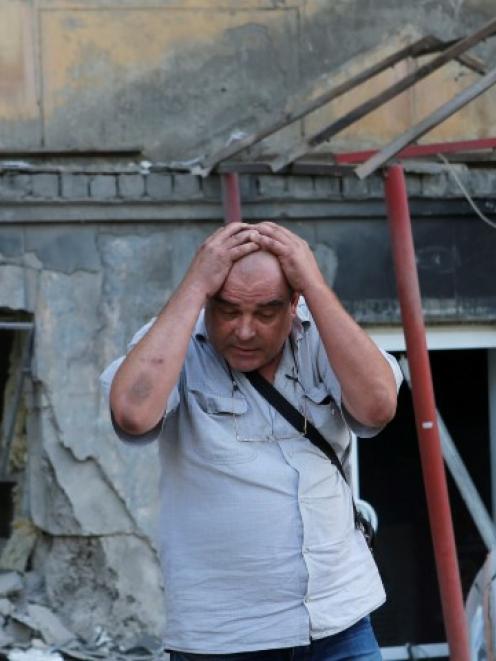 A man reacts as he stands in front of a building damaged by, what locals say, was recent shelling...