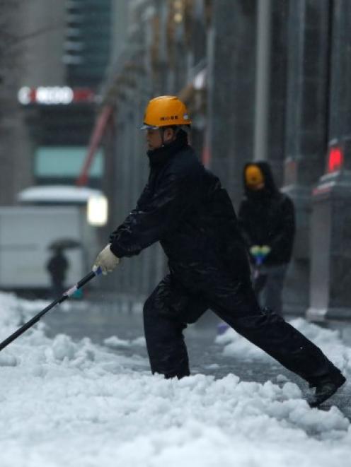 A man shovels snow on Tokyo street. REUTERS/Yuya Shino