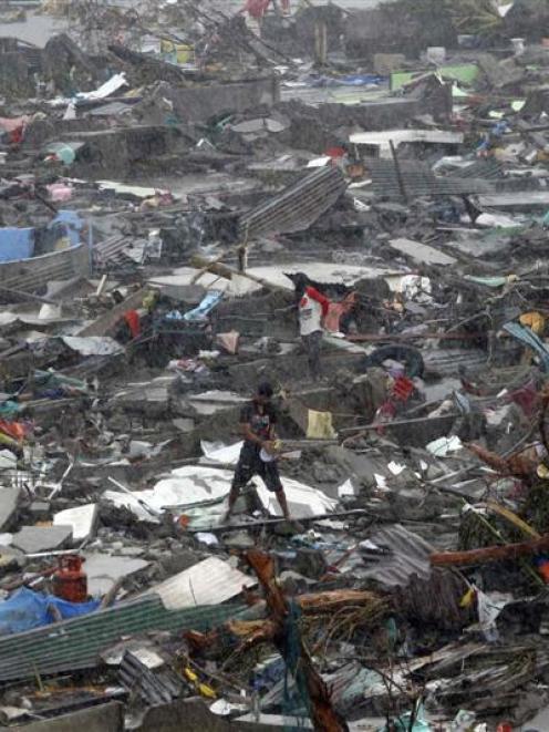 A man stands atop debris as residents salvage belongings from the ruins of their houses  after...