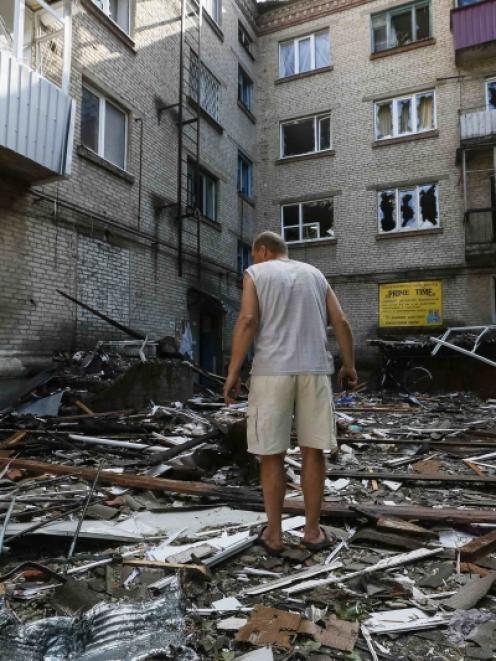 A man stands on debris near his destroyed house following what locals say was overnight shelling...