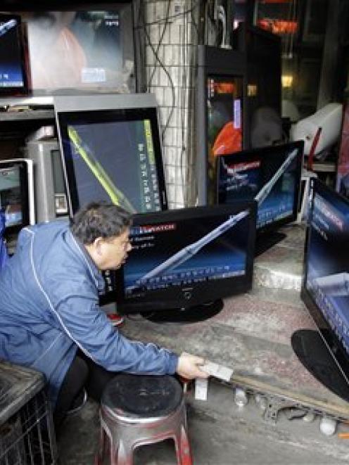 A man watches TV news showing a computer-generated simulation of North Korea's rocket launch at a...