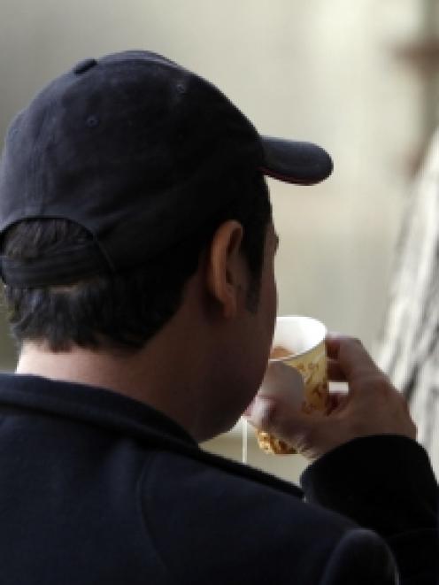 A man who goes by the name Haifa drinks tea with his back to the camera so as not to be...