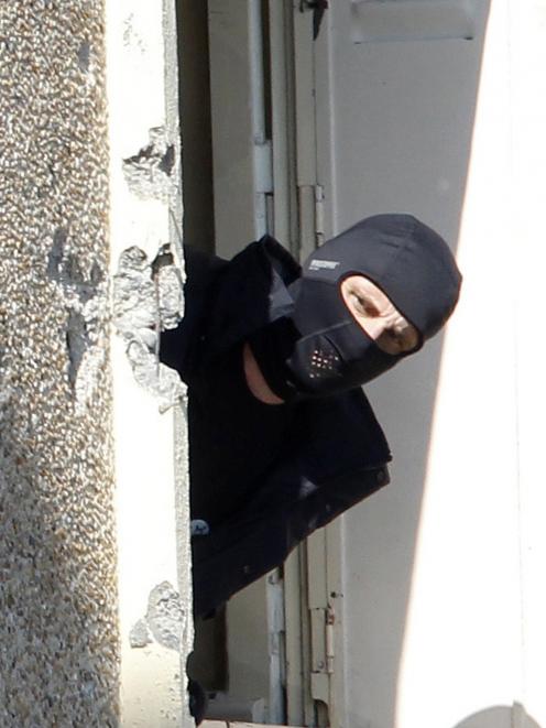 A masked French special unit policeman looks out of one of the ground floor window where special...