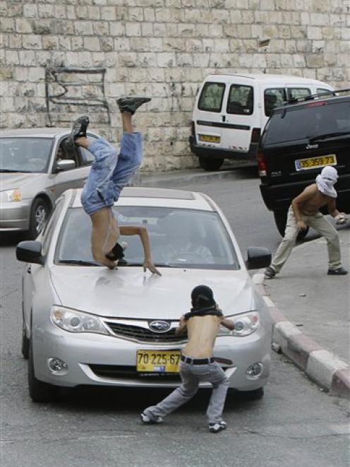 A masked Palestinian protester is hit by a car while throwing rocks in the east Jerusalem...