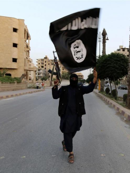 A member loyal to Islamic State waves the group's flag in Raqqa, Syria. Photo by Reuters
