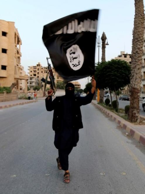 A member loyal to the Islamic State in Iraq and the Levant waves an ISIL flag in Raqqa, Syria....