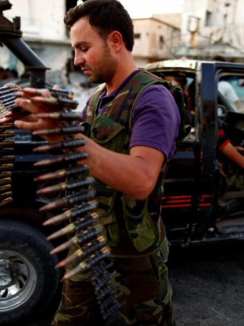 A member of the Free Syrian Army carries ammunition as he prepares for their patrol in Attarib,...