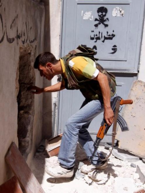 A member of the Free Syrian Army walks trough a hole during clashes with Syrian government forces...