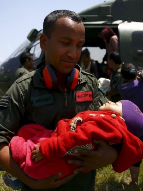 A Nepalese army personnel holds the baby of an earthquake victim after being airlifted from...