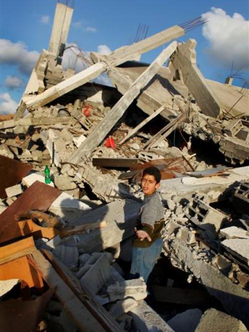 A Palestinian child gestures as he looks for belongings in the remains of his destroyed house in...