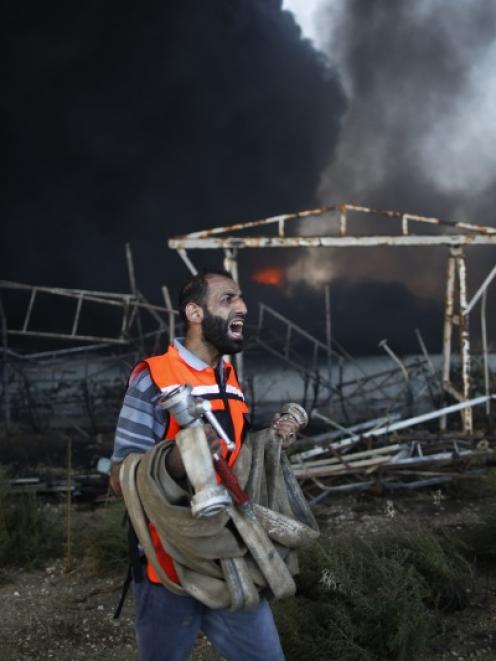 A Palestinian firefighter reacts as he tries to put out a fire at Gaza's main power plant, which...