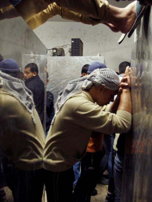 A Palestinian man is reflected in a hospital morgue as he reacts to the death of a relative in an...