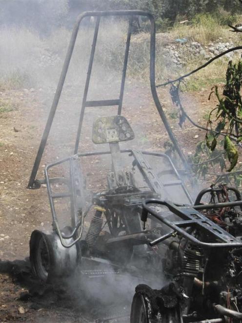 A Palestinian man looks at the remains of a quadbike set on fire by Palestinians after it was...