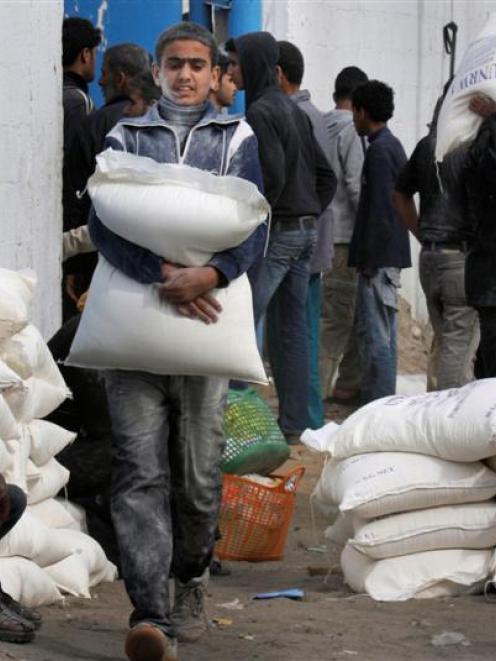 A Palestinian youth carries flour after he received it at a United Nations food distribution...