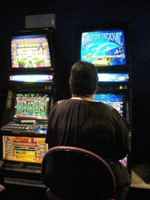 A pokie player  generates cash. Photo by Jane Dawber.