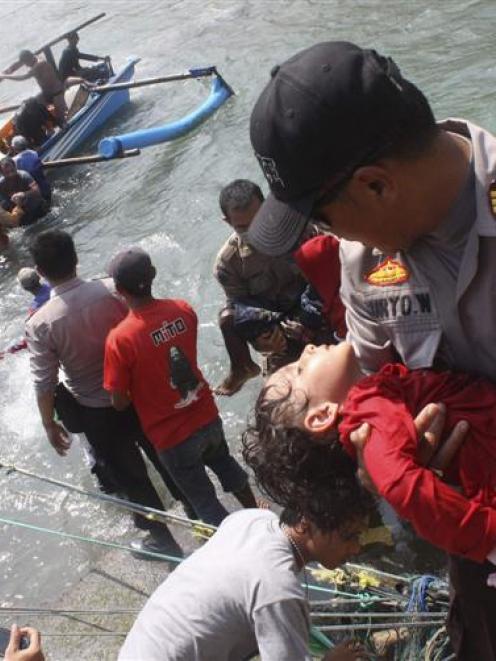 A police officer carries an unconscious child who was on a boat that capsized late off the coast...