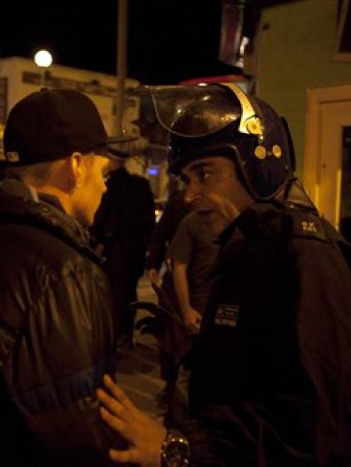 A police officer searches a man as members of the community march to reclaim their streets after...