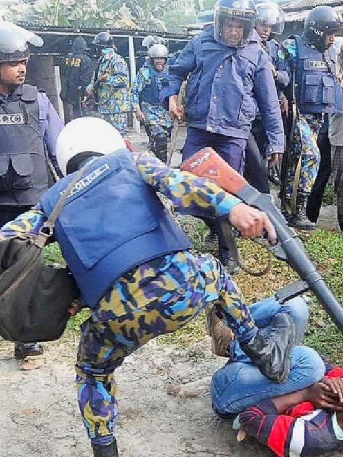 A policeman kicks a protester during a clash after protesters attacked and set fire to polling...