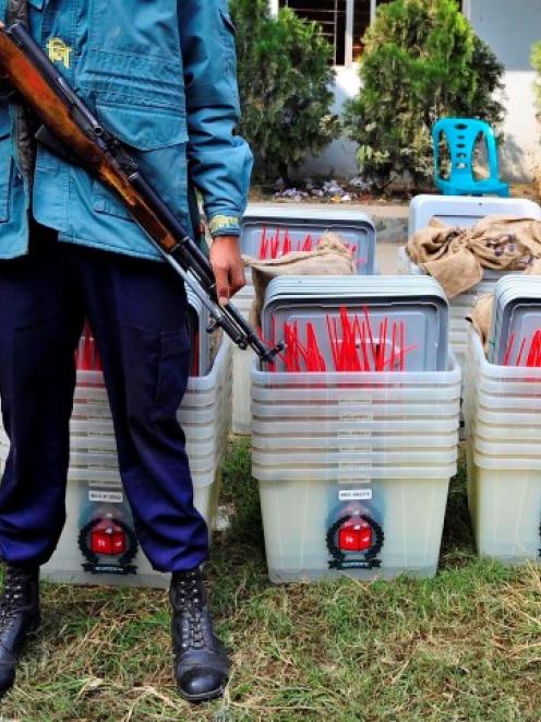 A policeman stands guard in front of ballot boxes at a distribution centre ahead of parliamentary...