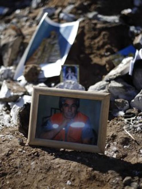 A portrait of Mario Gomez, one of 33 trapped miners, sits next to cards bearing religious...