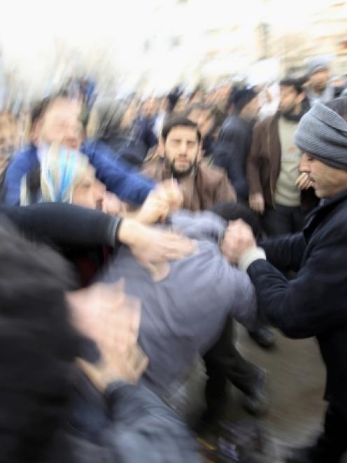 A pro-Assad policeman is beaten by protesters during the funeral of Mazen abou Dhahab, who was...