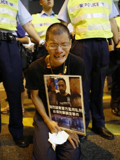 A pro-democracy protester cries as he holds a placard with photos of Ken Tsang Kin-chiu, a...